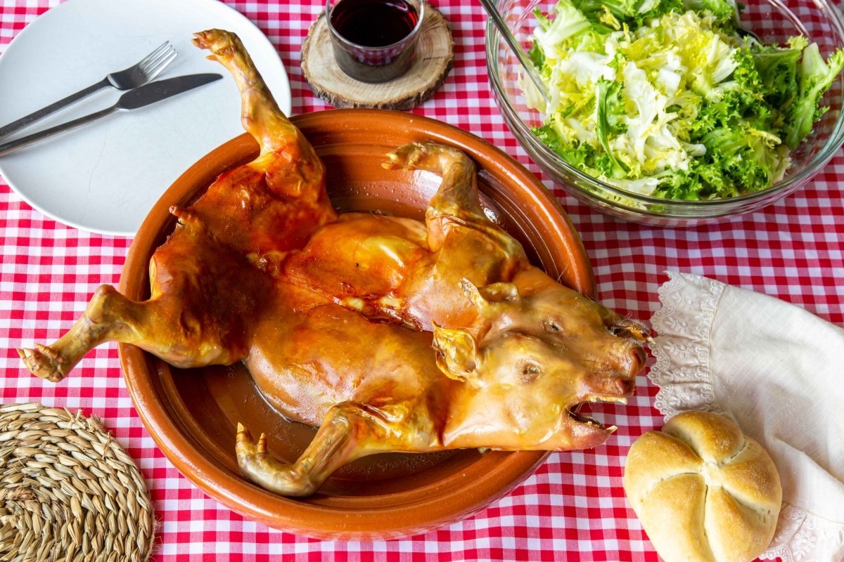 Un cerdo en cazuela de barro con ensalada y pan.