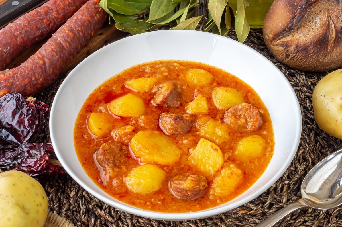 Un plato de guiso con patatas y salchichas.